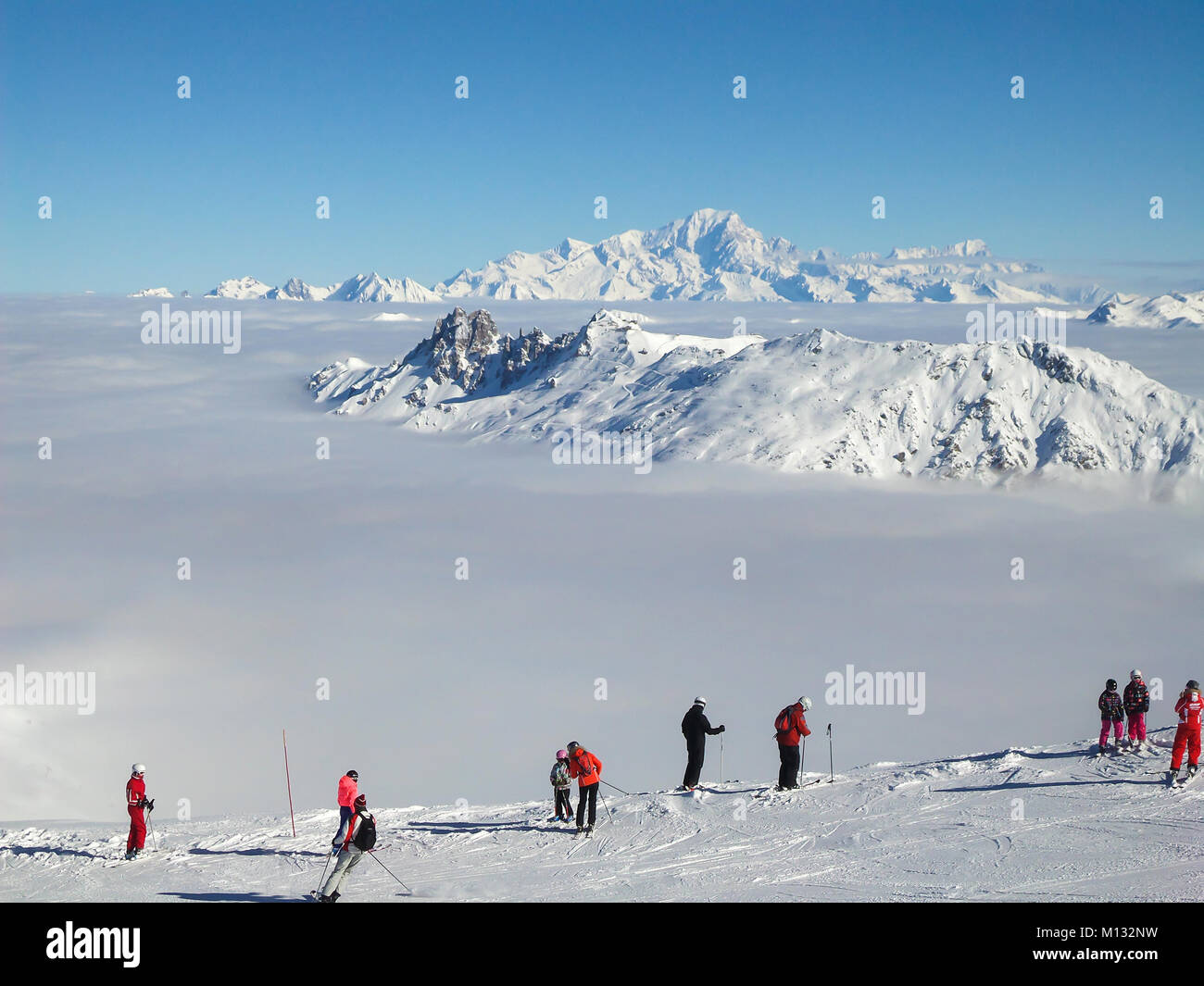 Skiers looking at the Mont Blanc over a sea of clouds, the Alps, France Stock Photo