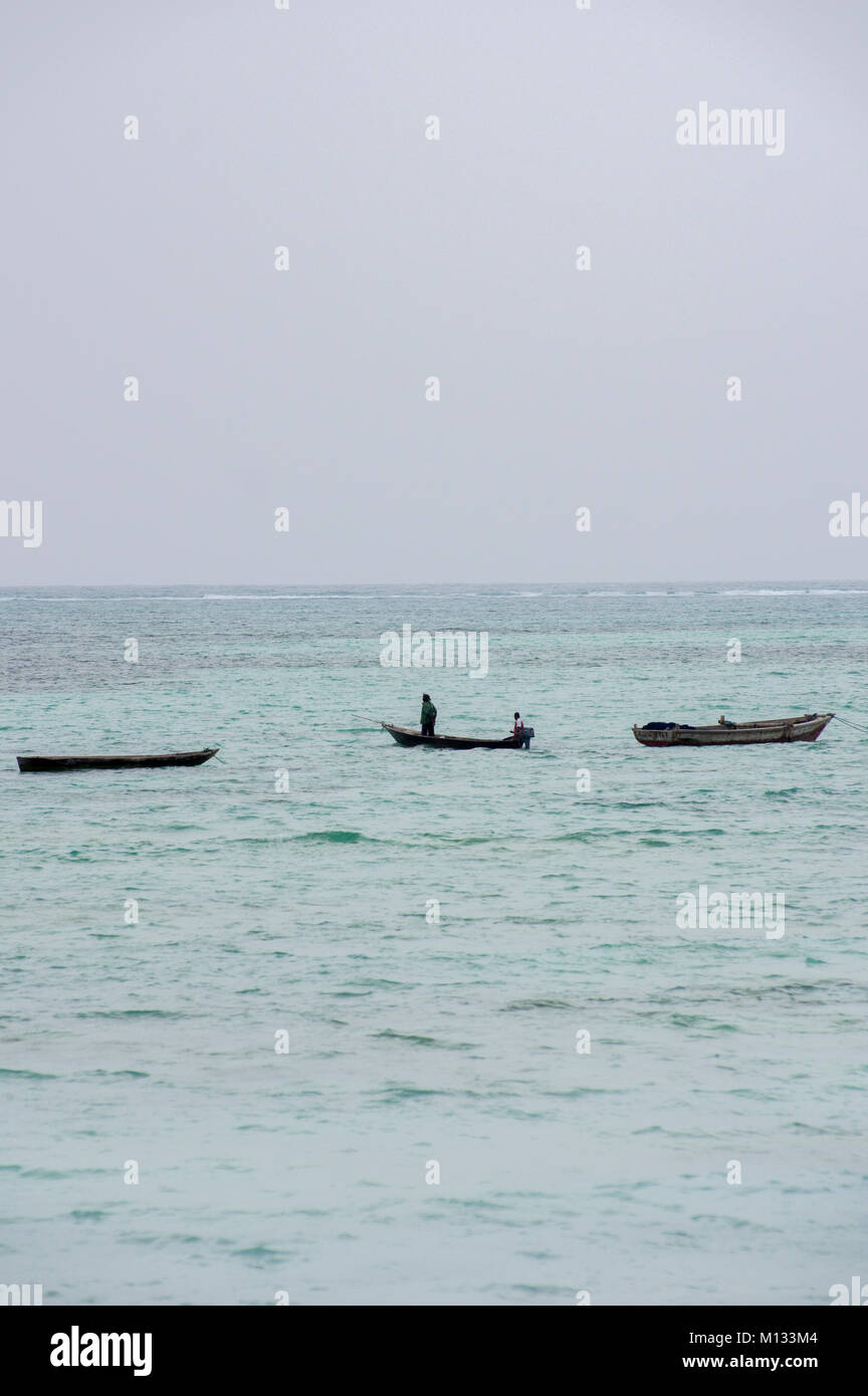 Fishermen going out to sea in traditional dhow boats in Nungwi on the island of Zanzibar with turquoise waters of the Indian Ocean Stock Photo