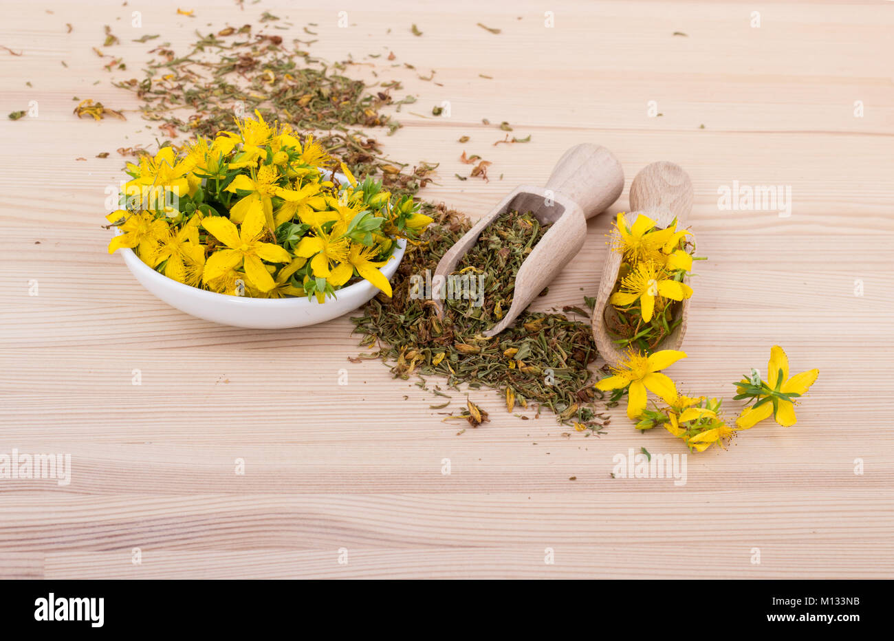 dried and fresh, flowering St. John's wort with bowl and spoons on a wooden background Stock Photo