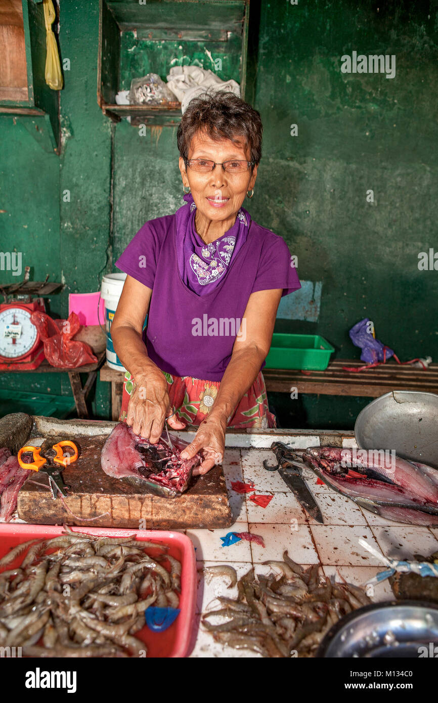 A senior age Filipino woman works in her fish stall splitting Bangus, a