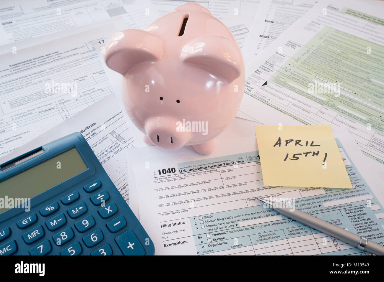 IRS Federal Tax Forms with Piggy Bank, Calculator, Pen and Reminder Note Stock Photo