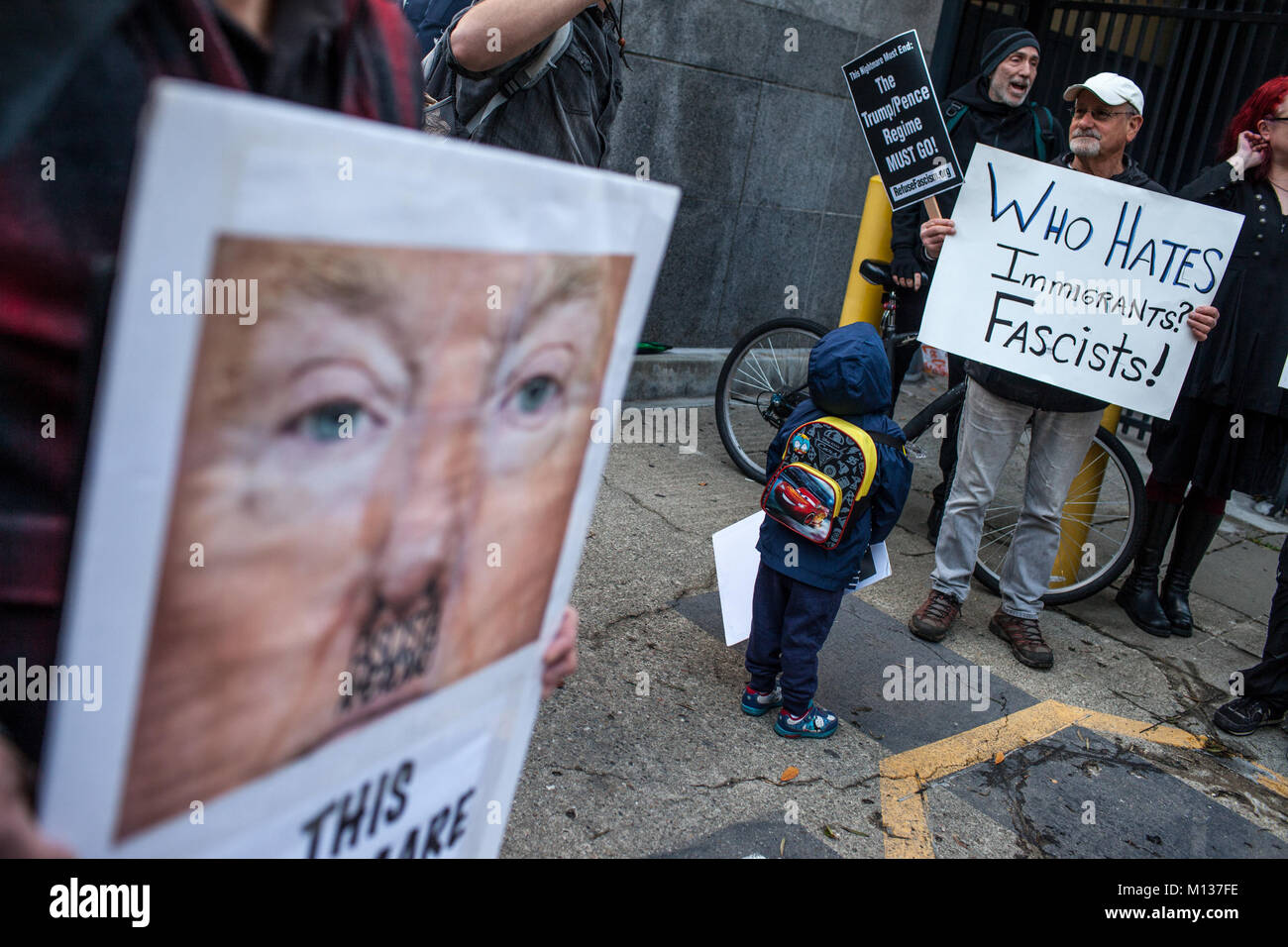 San Francisco, California, USA. 25th Jan, 2018. ALEXANDER RAMOS, 3, looks at BRUCE NEUBURGER, 70, as he holds a sign during a protest against immigration raids outside the Immigration and Customs Enforcement headquarters in downtown San Francisco, California. Credit: Joel Angel Juarez/ZUMA Wire/Alamy Live News Stock Photo