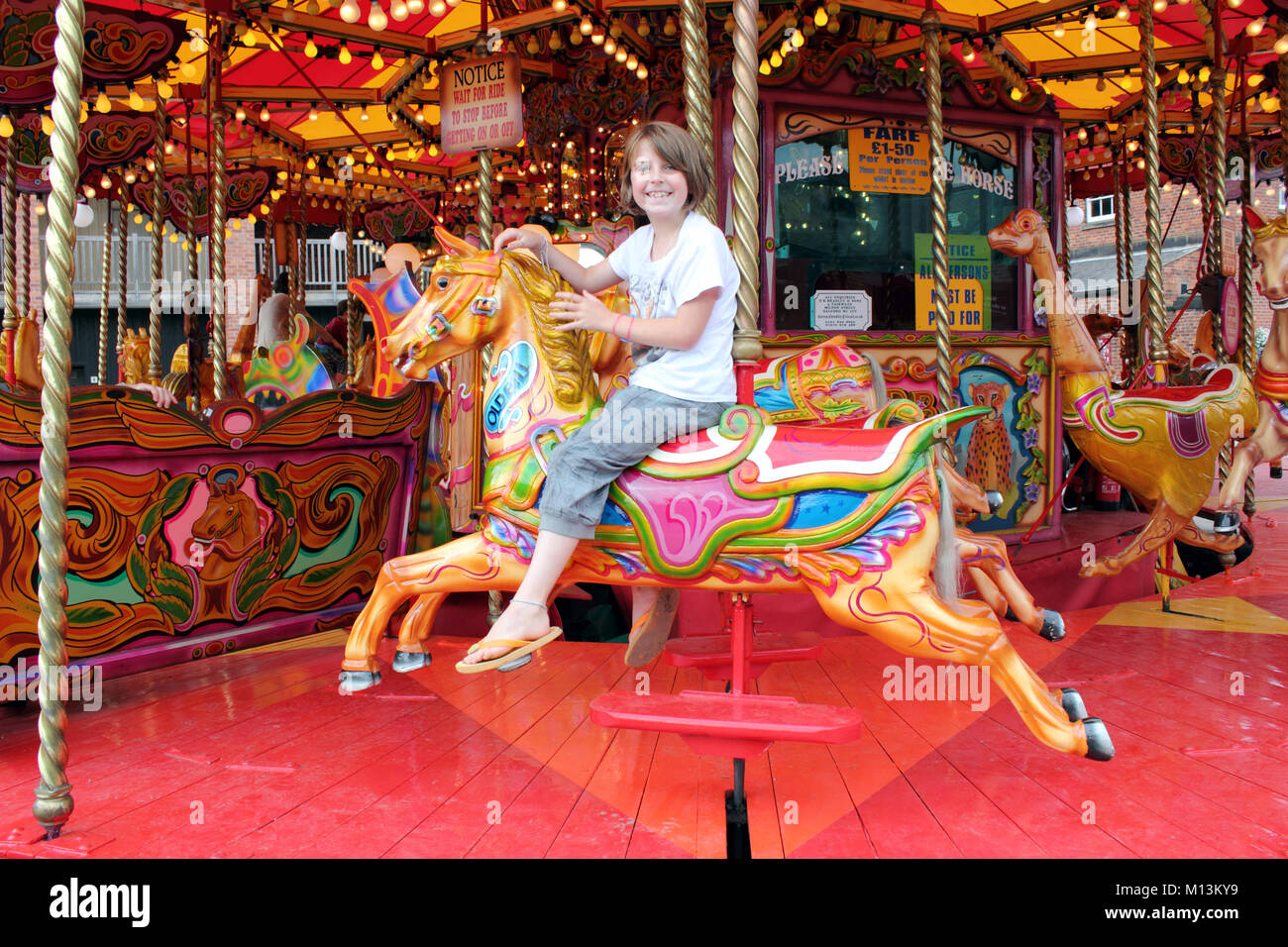 Landscape view of pretty, smiling  teenage girl on carousel Stock Photo