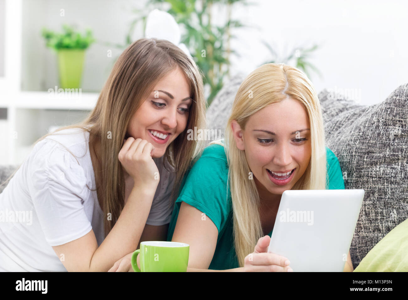 two happy young women with digital tablet Stock Photo - Alamy