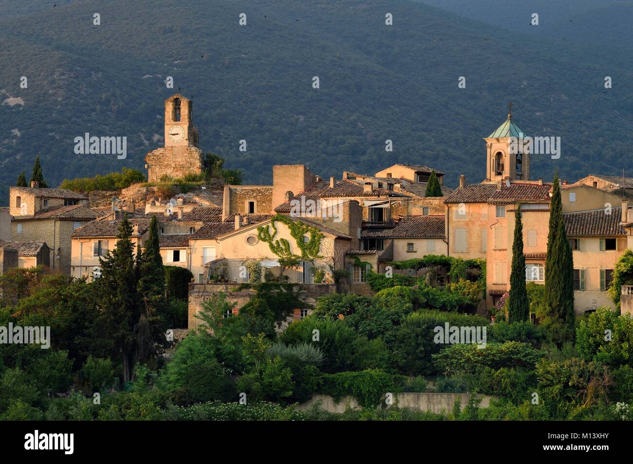 France, Vaucluse, Parc Naturel Regional du Luberon (Natural Regional Park of Luberon), Lourmarin, labelled Les Plus Beaux Villages de France (The Most Beautiful Villages of France), the clock tower and the church bell tower, the massif of Luberon in background Stock Photo
