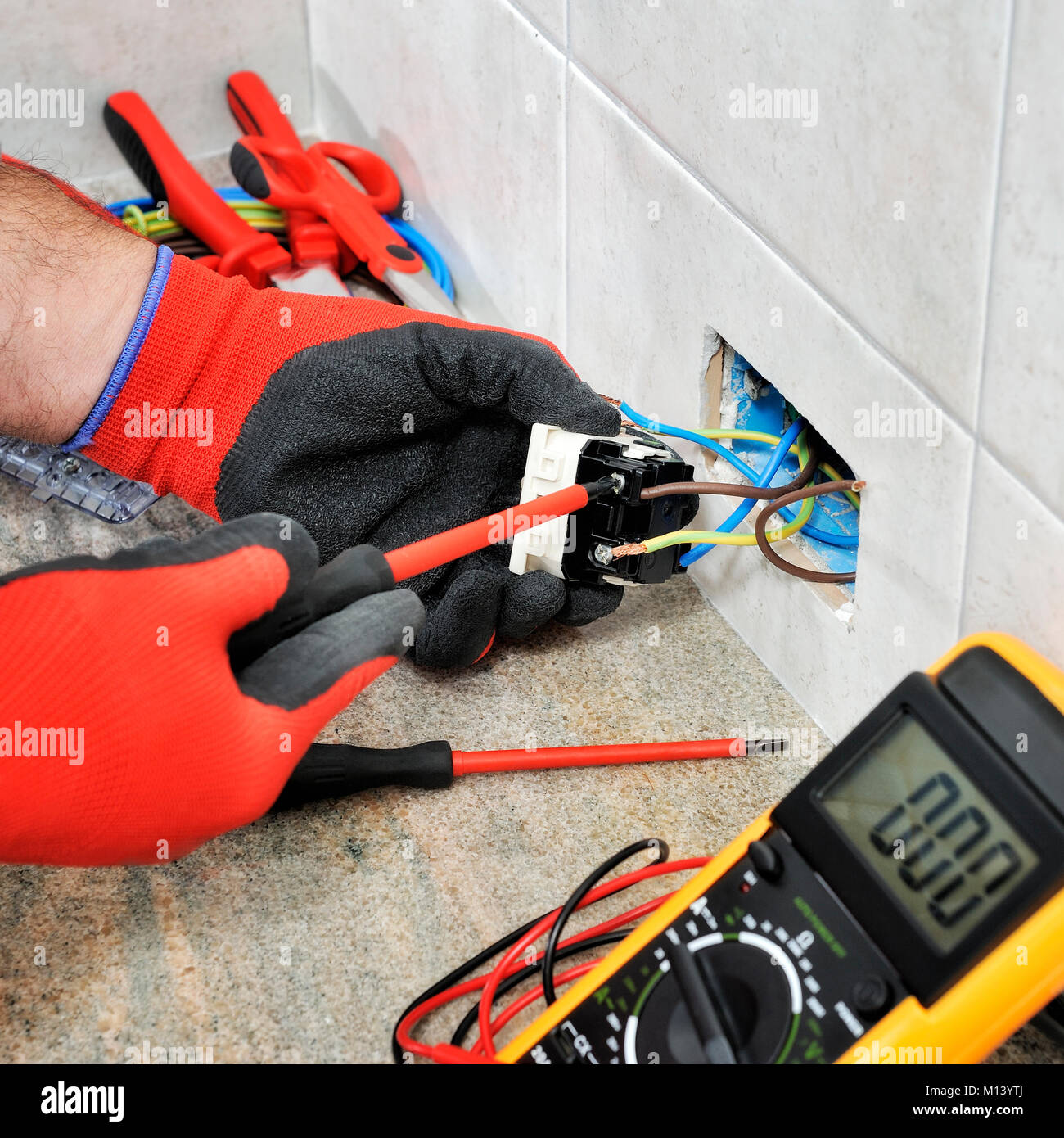 Electrician technician with gloves and safety instruments fixes the  electric cable to the socket of a residential installation Stock Photo -  Alamy