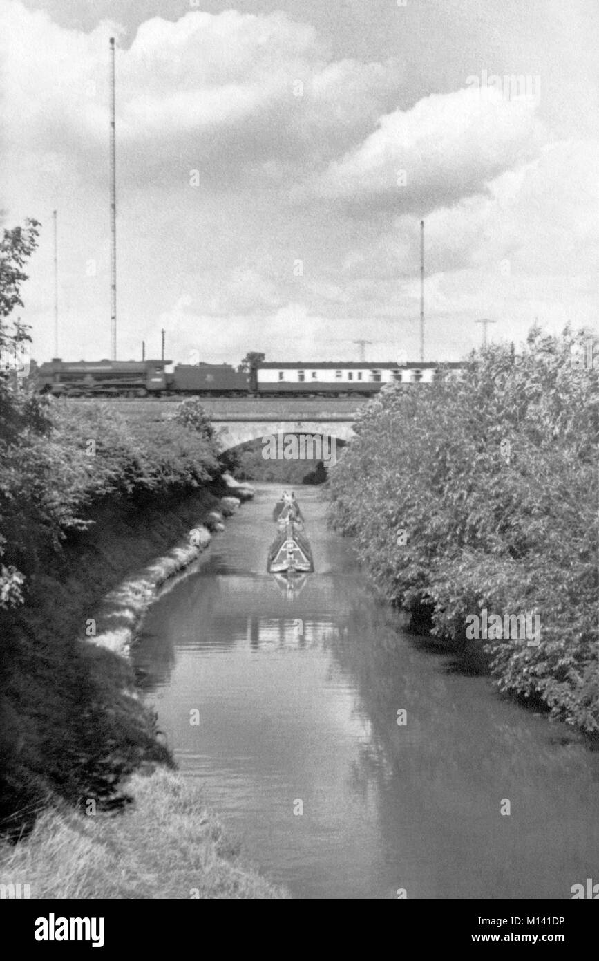 brithish rail steam loco crossing bridge over the oxford canal with narrow boats below and rugby radio masts in the background 1960s england uk Stock Photo