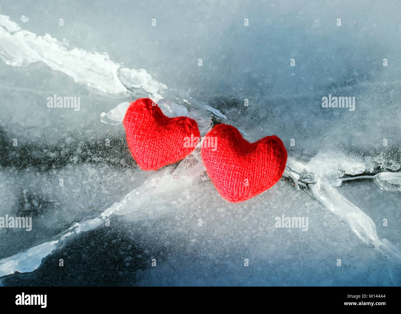 two warm red heart of the yarn on the crack the cold blue ice Stock Photo