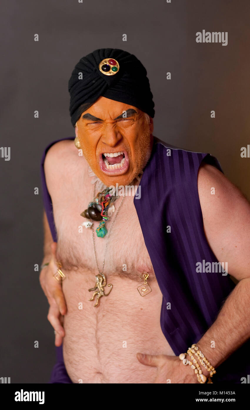 Angry, orange faced man in a purple vest and black turban. Stock Photo