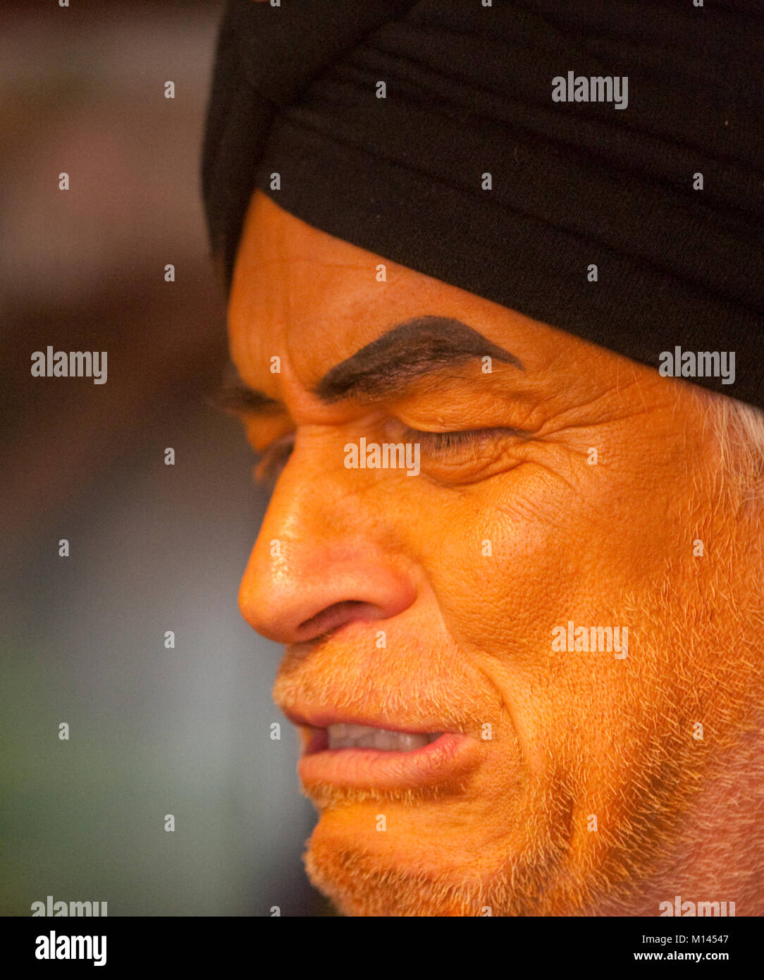 Orange faced man in a purple vest and black turban. Stock Photo