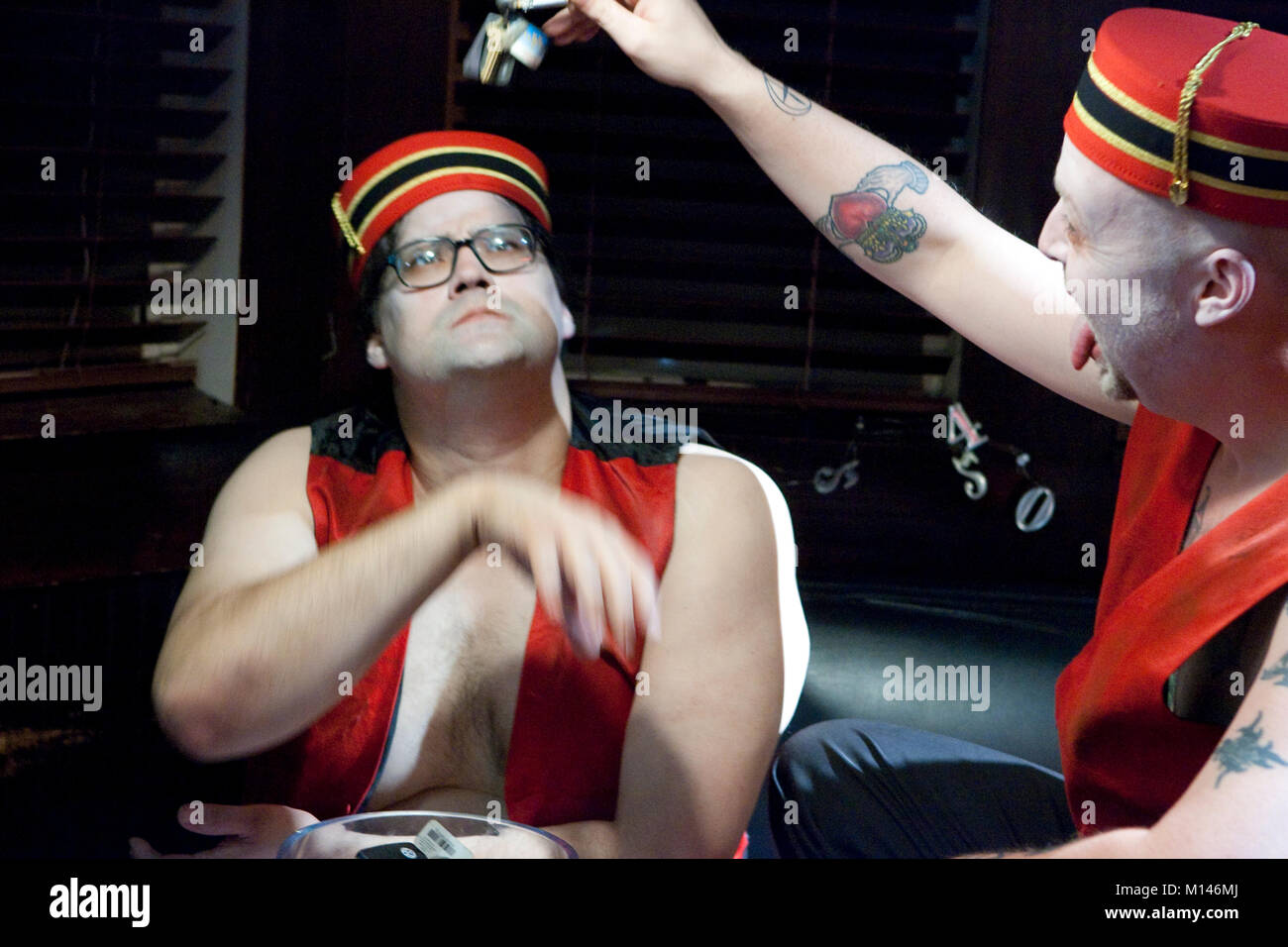 two hotel valets, dressed in red uniforms, playing with car keys Stock