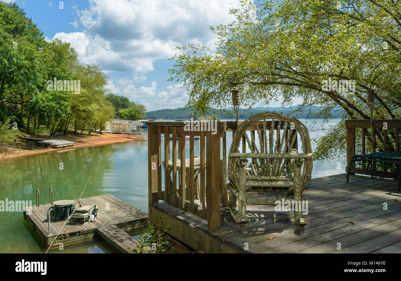 Rustic rocking chair on wooden deck under shade of tree on bank of lake in Smoking mountains in summer near Blue Ridge, Georgia, USA. Stock Photo