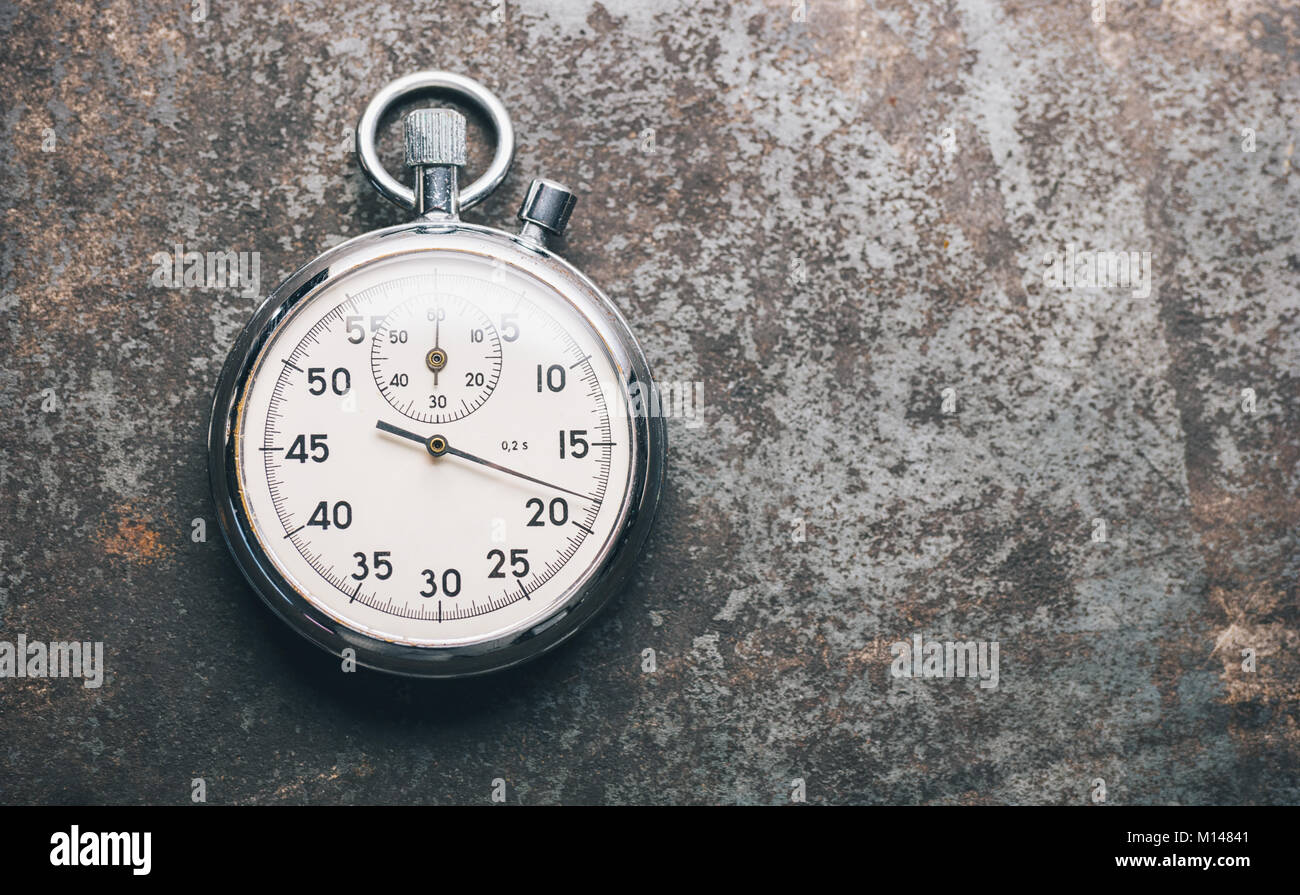 silver stopwatch lies on a weathered background. Stock Photo
