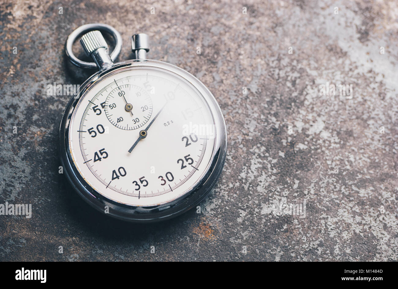 classic silver stopwatch lies on a weathered background. Stock Photo