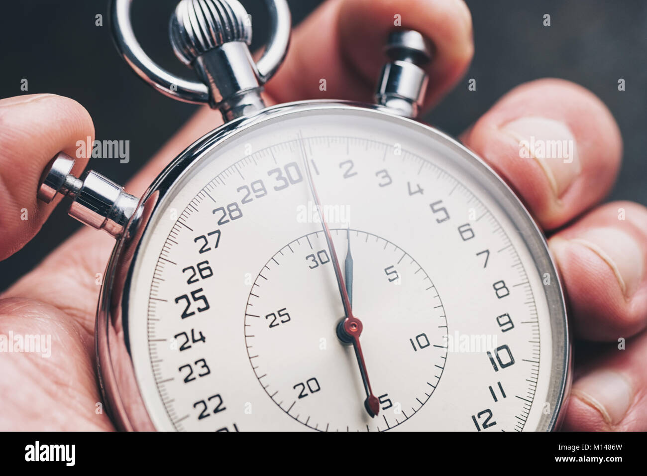 close view of a male hand holding a stopwatch to measure time. Stock Photo