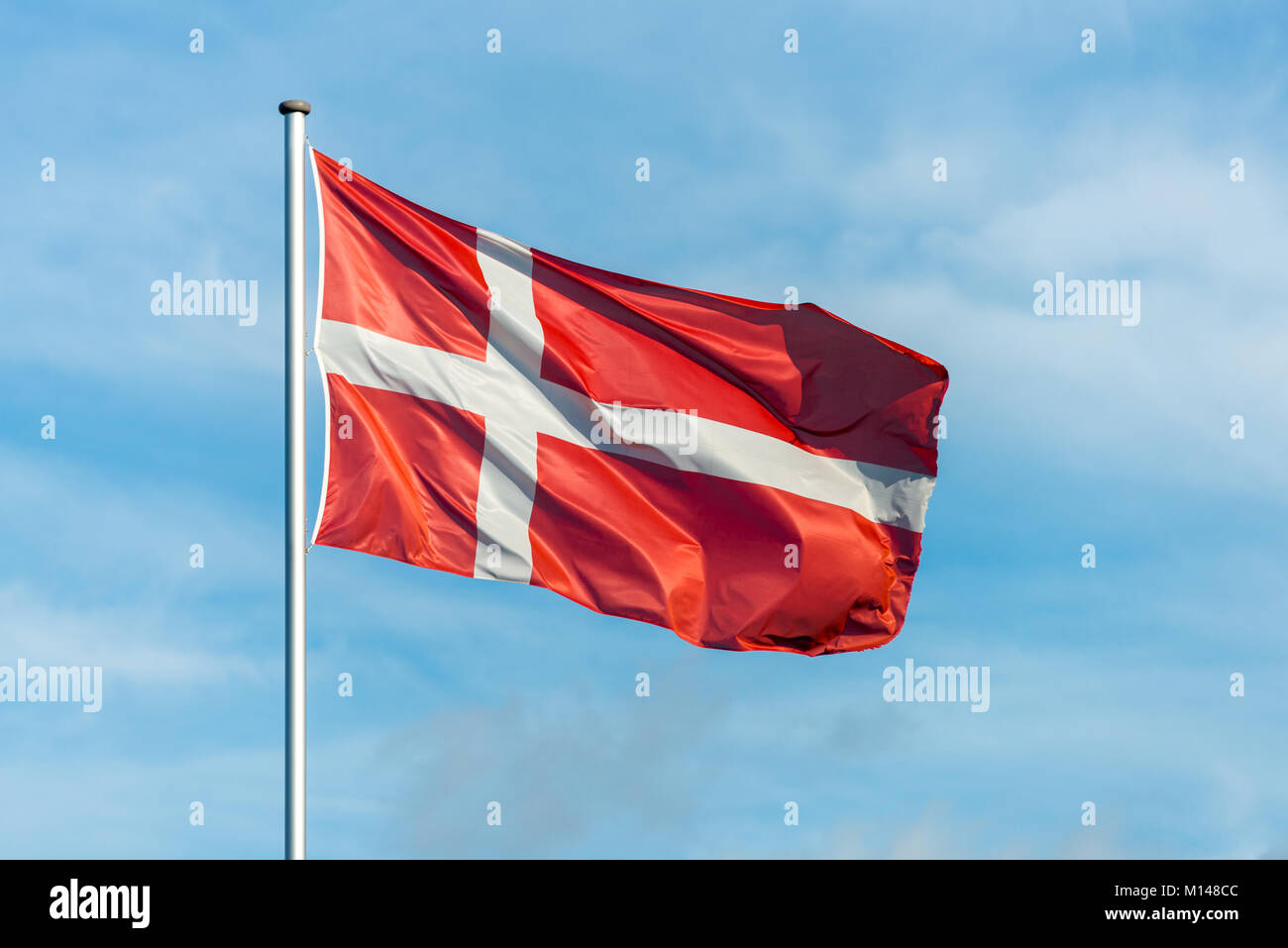 Closeup of single danish flag waving in the wind in front of blue sky Stock Photo
