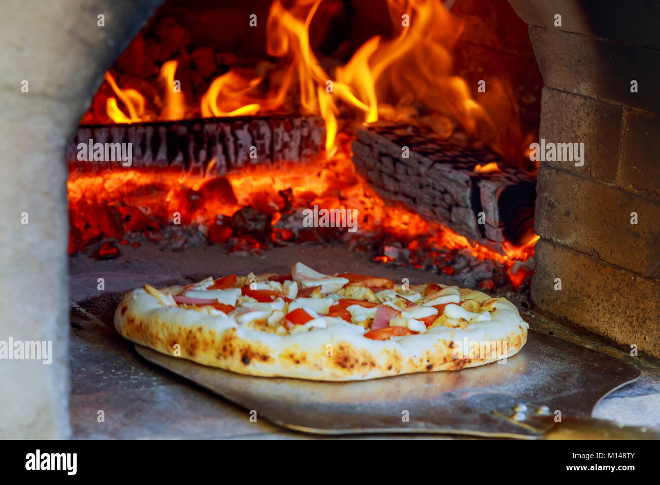 Close up pizza in firewood oven with flame behind Stock Photo - Alamy