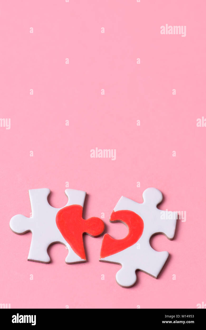two separated pieces of a puzzle which together form on a pink background with a blank space on top, depicting the idea of rupture or cooperation Stock Photo