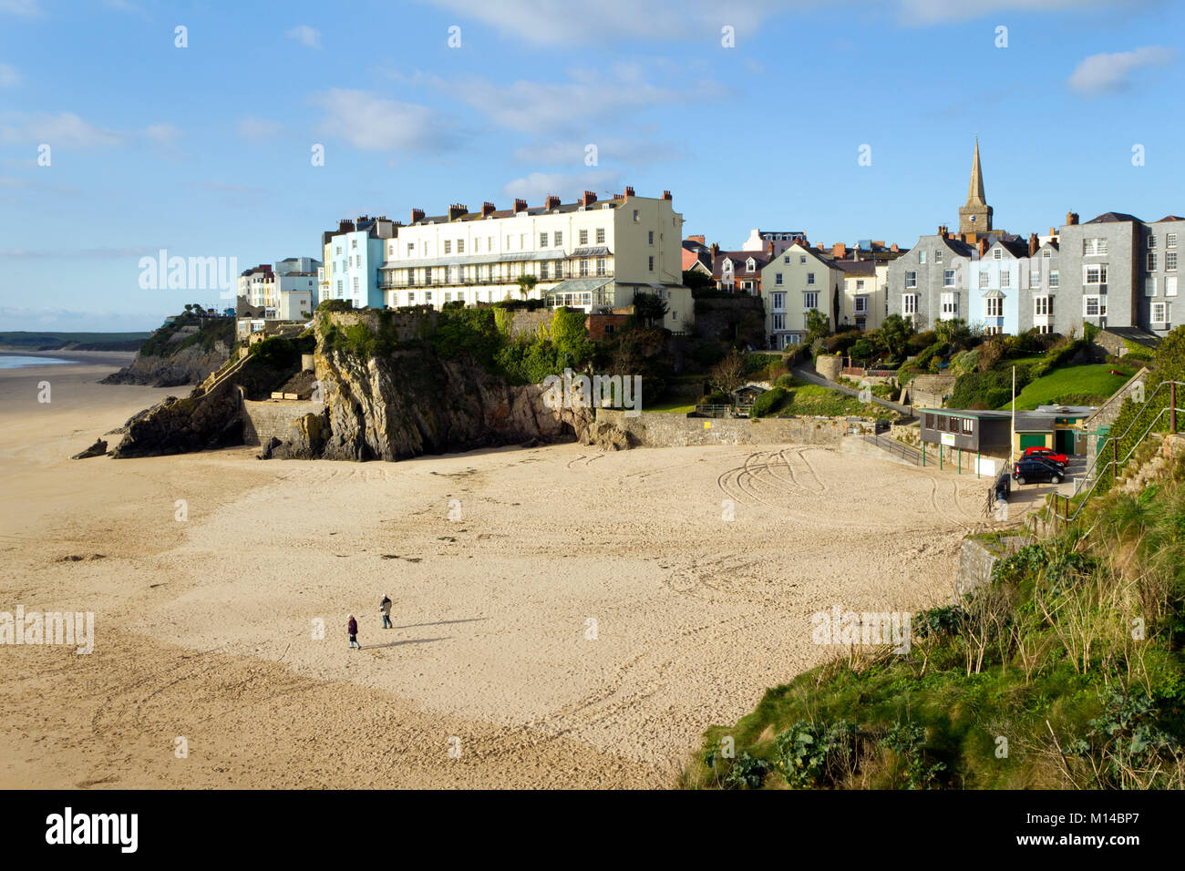 Tenby, UK - 7th November 2011: A couple walk out in November sunshine on an empty Castle Beach at Tenby, Pembrokeshire, Wales, UK. Tenby experiences a maritime climate with cool summers and mild winters and is one of the sunnier locations in Wales. Stock Photo