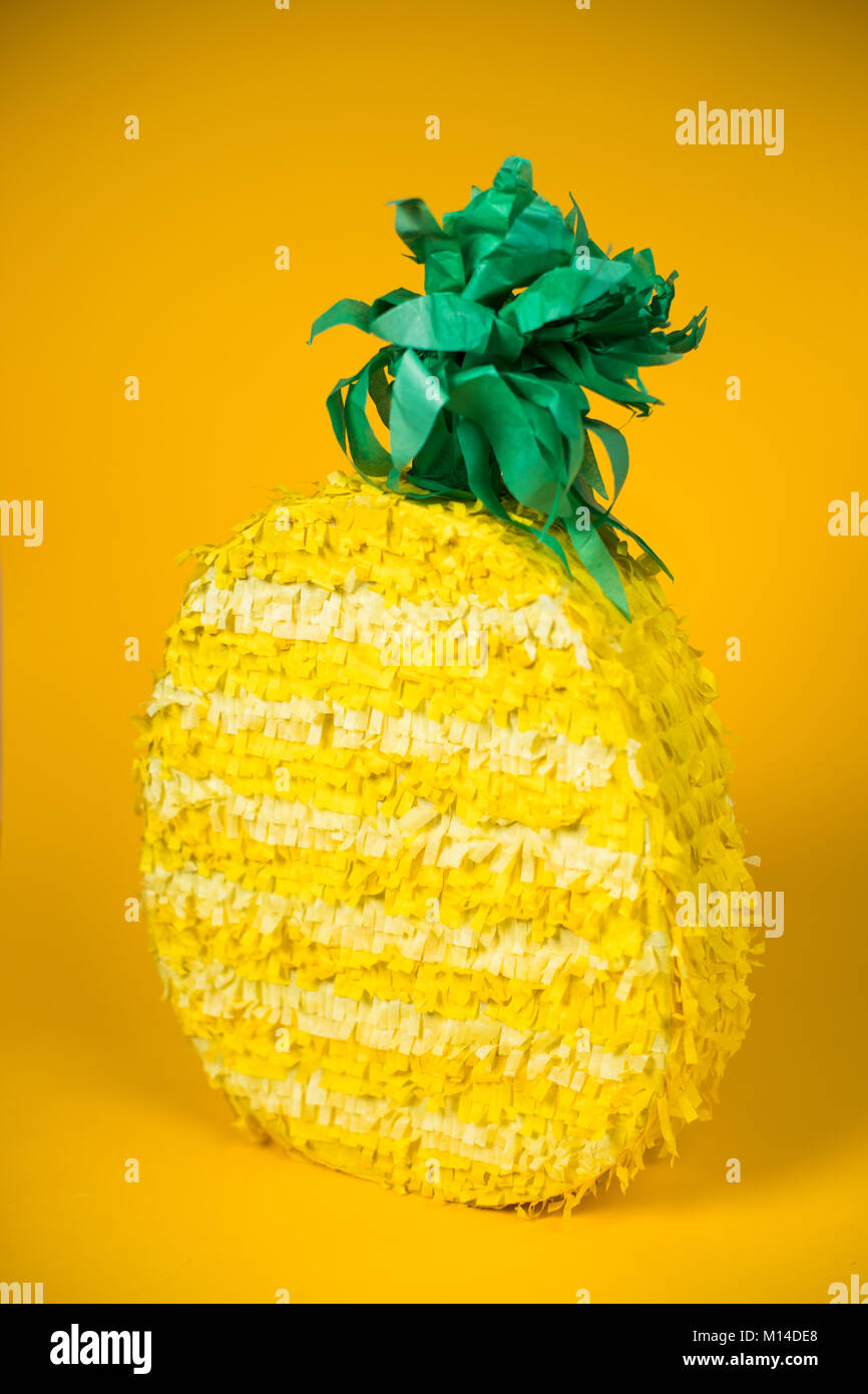 A pineapple piñata among a yellow backdrop Stock Photo