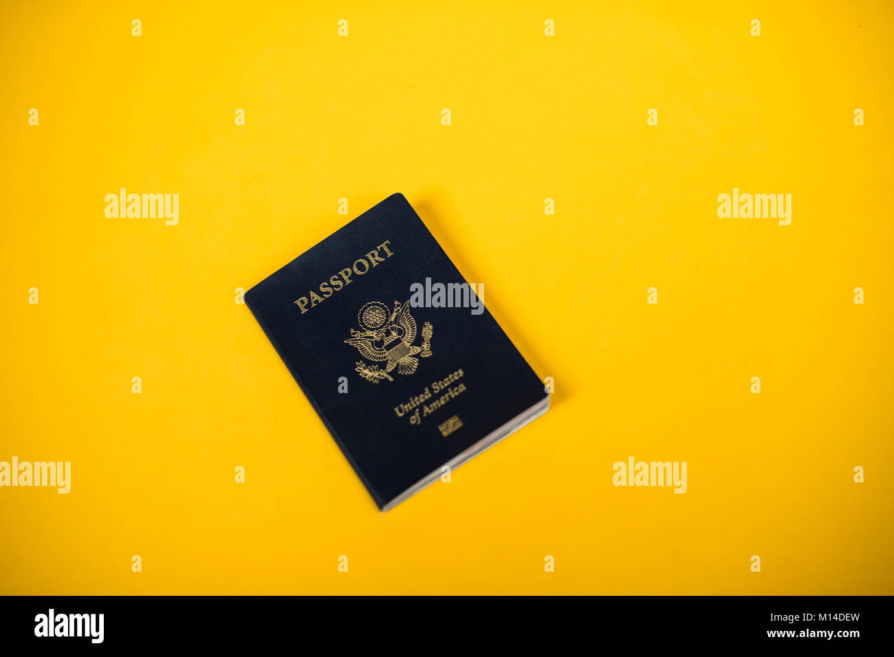 a United States of America passport laying on a yellow backdrop Stock Photo