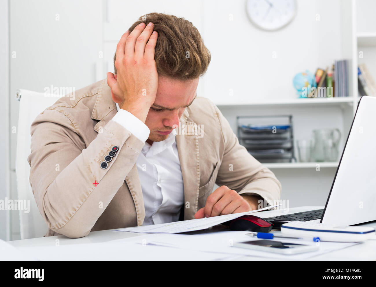 Frustrated young man having business problems with papers at workplace ...