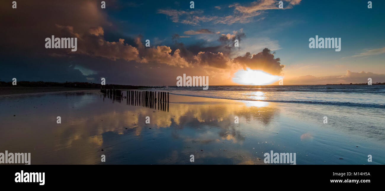 Stormy clouds with sun rays just before sunset on a winters day at West Head on West Wittering Beach Stock Photo