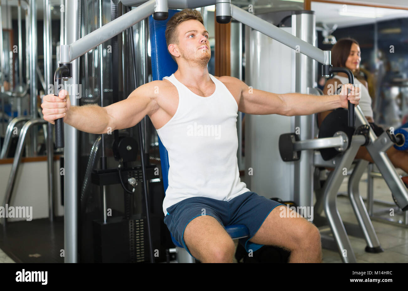 strong young man training upper body using fly machine in gym Stock Photo Alamy