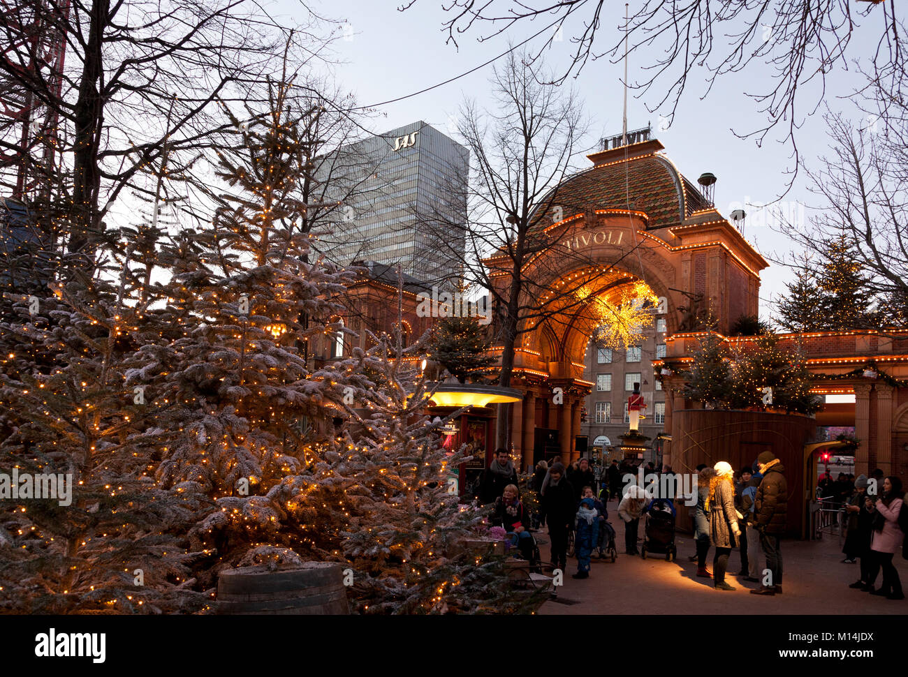 View out of main entrance of the Tivoli Gardens in Copenhagen at dusk during Christmas opening. The Radisson Blu Royal Hotel towering in background. Stock Photo