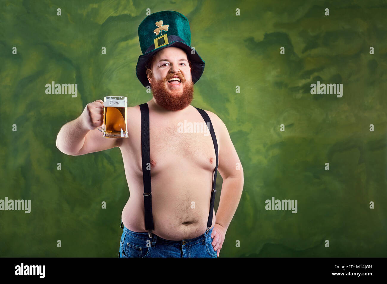 A fat man with a beard in St. Patrick's suit is smiling with a m Stock Photo
