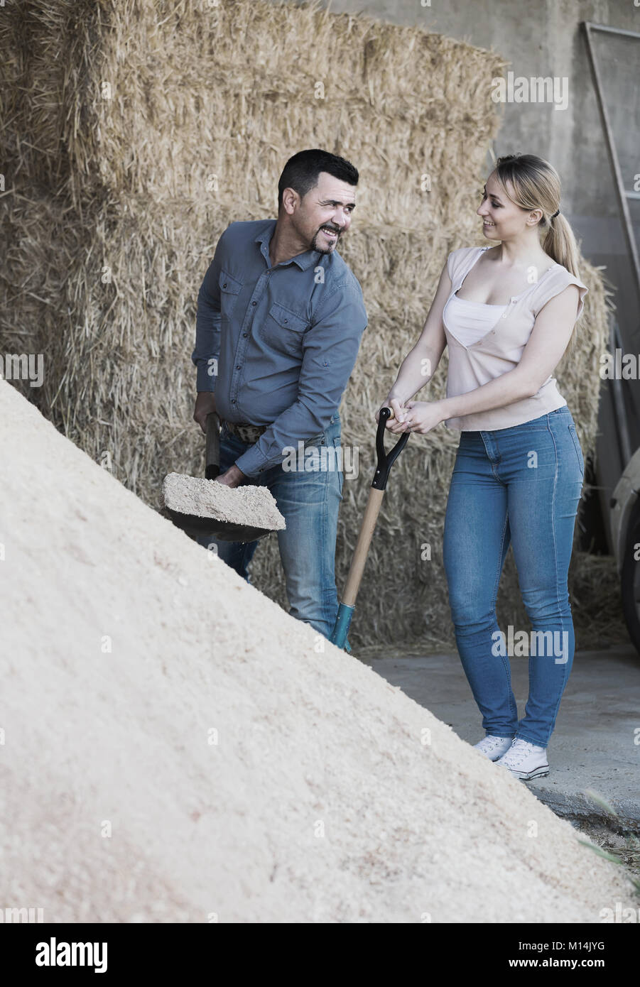 portrait of happy man and woman with shovel talking in farm housing