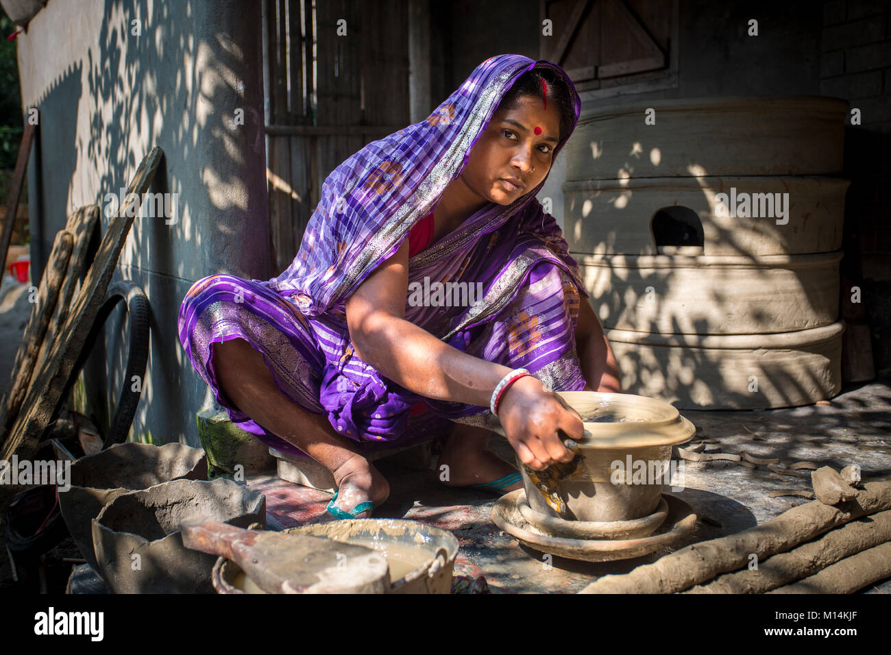 Kobita Rani Pal, 30, is making pots using clay at the Kumar Para (Potters community) in in Iswardi, Bangladesh. Stock Photo