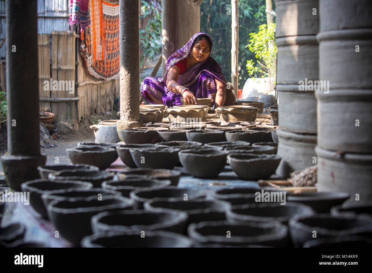 Kobita Rani Pal, 30, is making pots using clay at the Kumar Para (Potters community) in in Iswardi, Bangladesh. Stock Photo