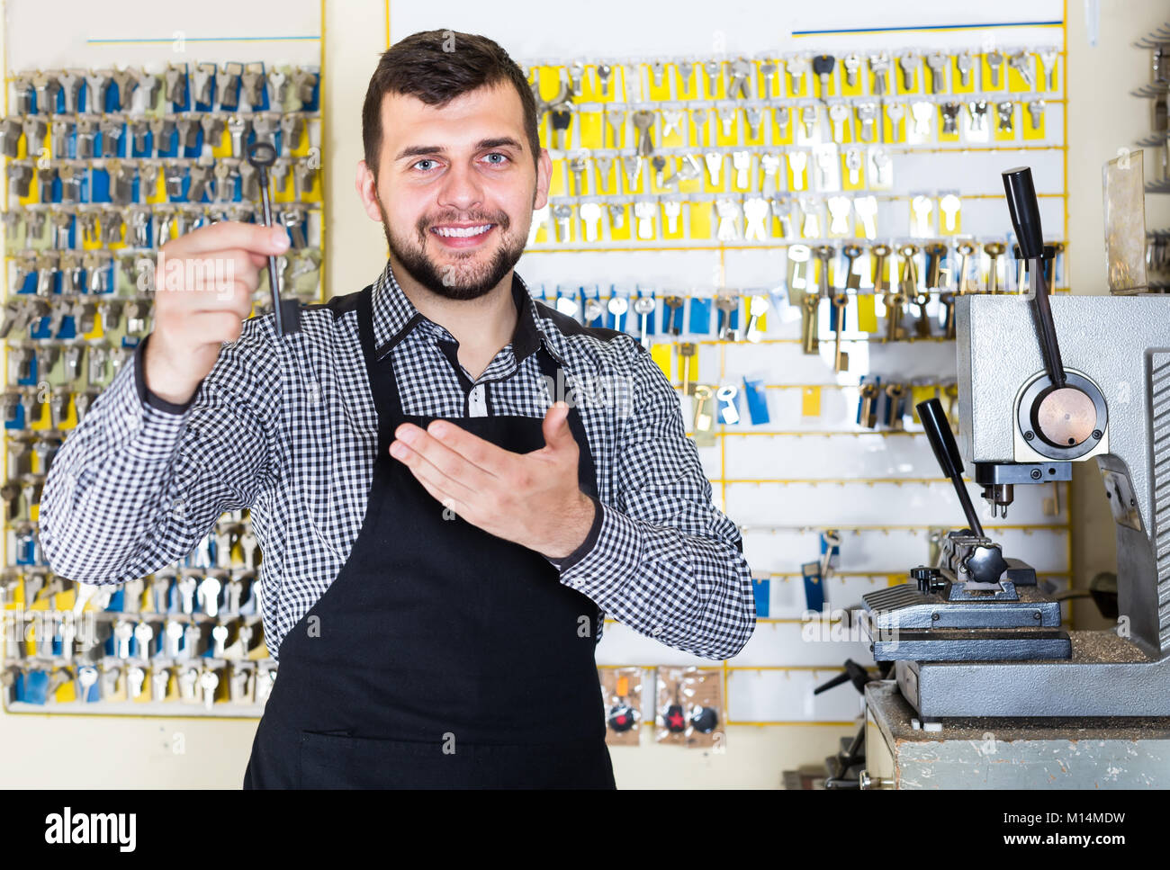 Keymaker Job Young man worker displaying result of his key making at his workplace ...