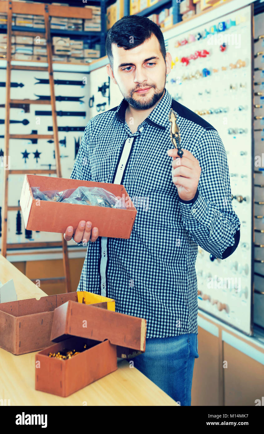 Smiling spanish male seller sorting boxes with door handles in