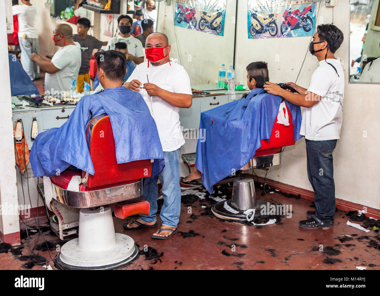 Filipino barbers at work in their barbershop in Barretto, Luzon, Philippines. Stock Photo