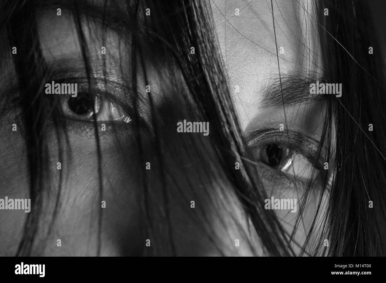 stared female eyes under blowing hair close up, monochrome Stock Photo