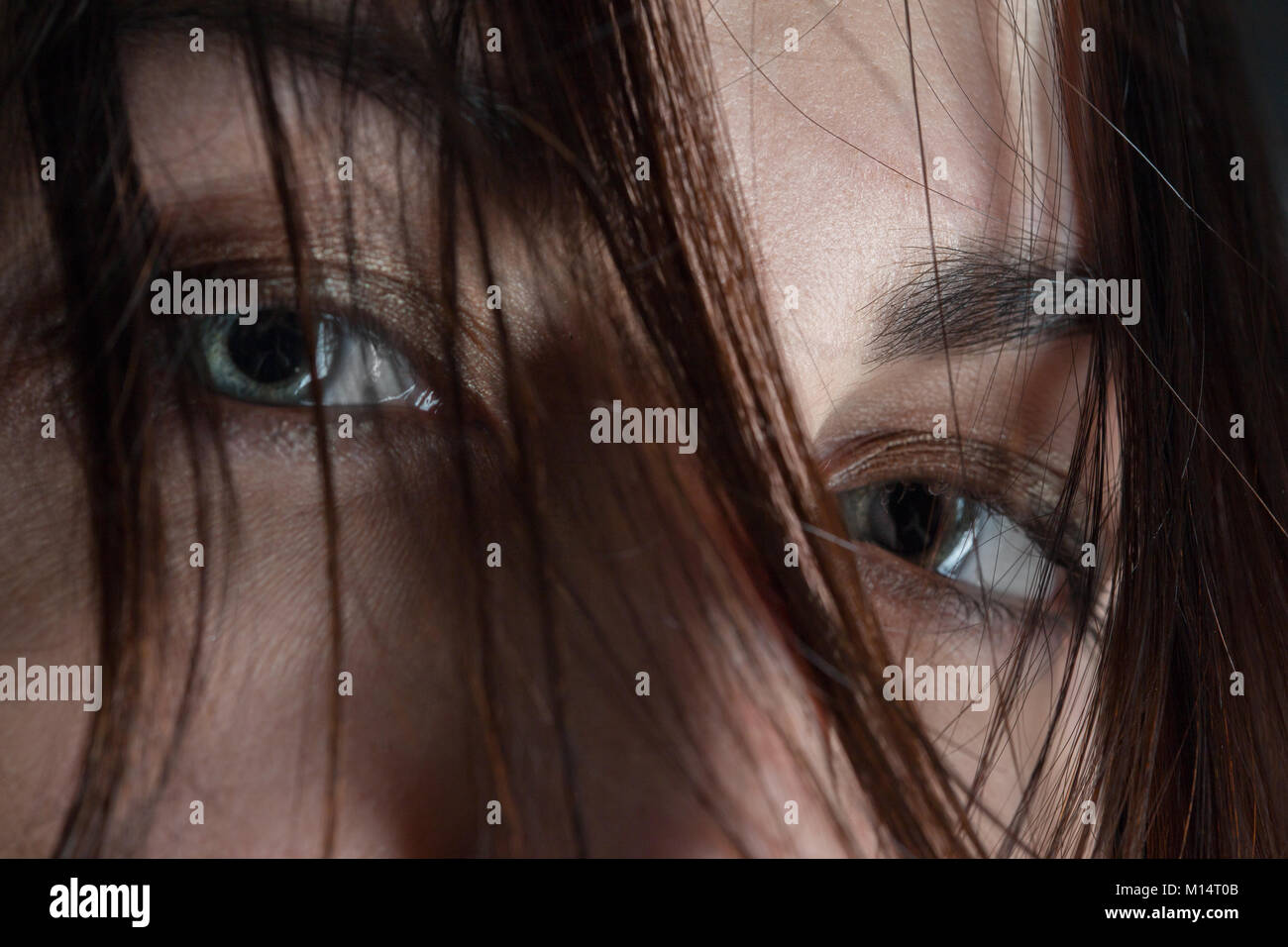 stared female eyes under blowing hair close up Stock Photo