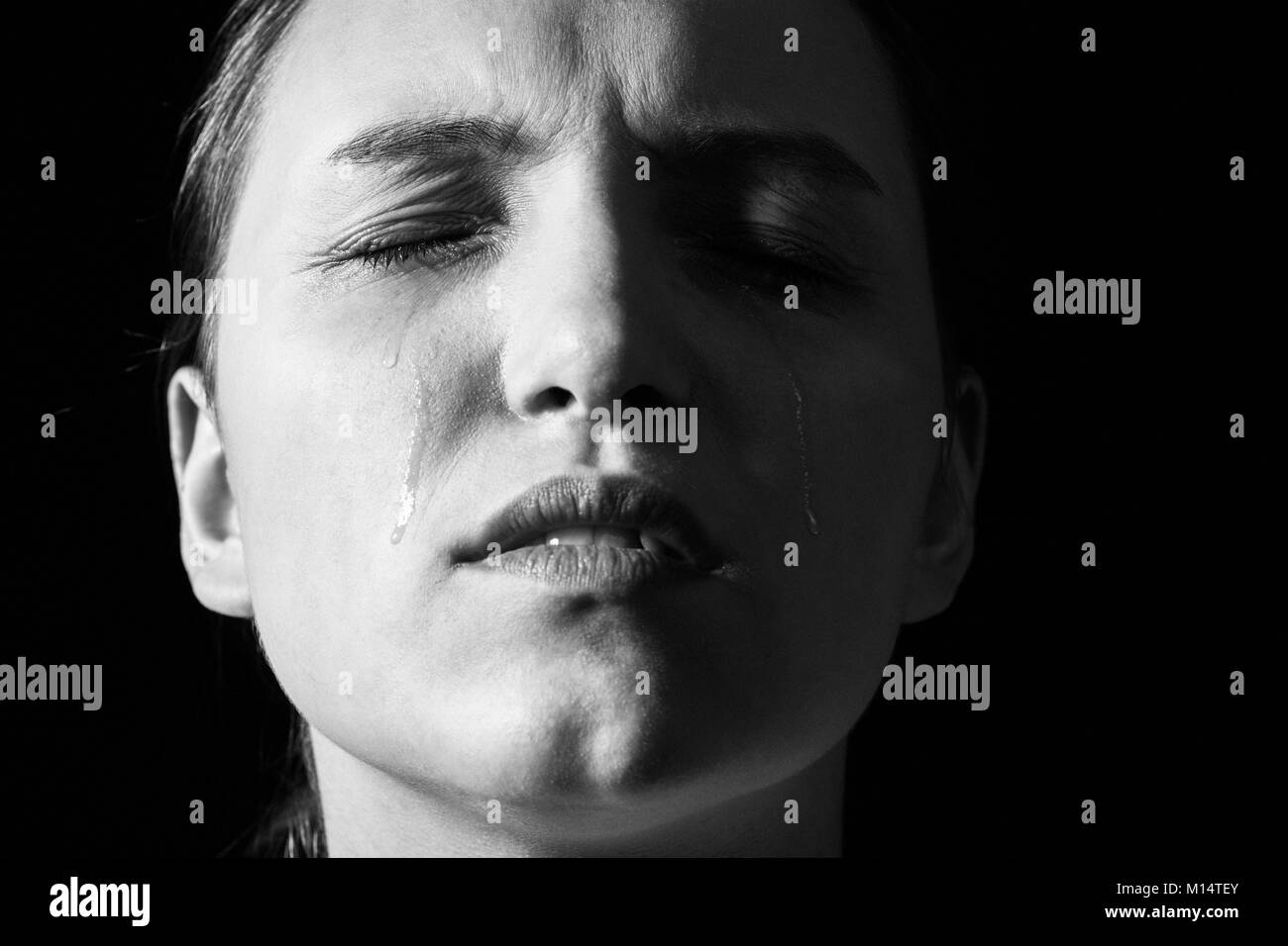 sad woman crying on black background, closeup portrait monochrome Stock Photo