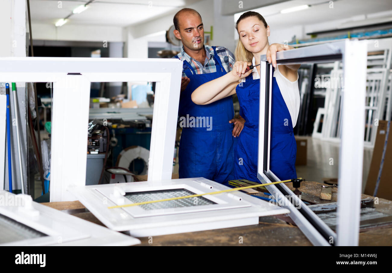 Cheerful young female assembler of metal-plastic windows consulting ...