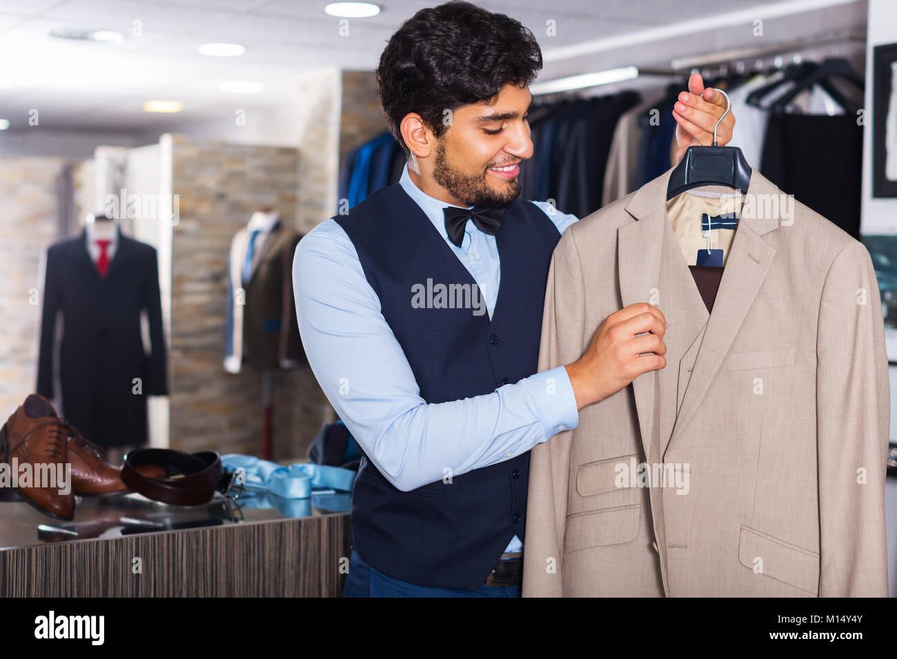 Portrait of young man choosing jacket in clothes shop Stock Photo - Alamy