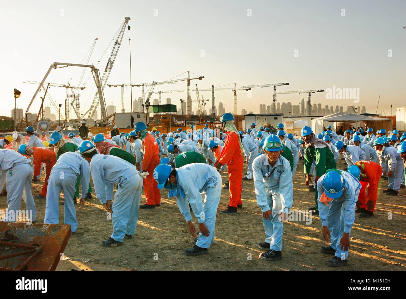 United Arab Emirates, Dubai, workers on construction site on Palm Jumeirah (2005) with the JBR towers of Dubai Marina and Al Sufouh towers in the background Stock Photo