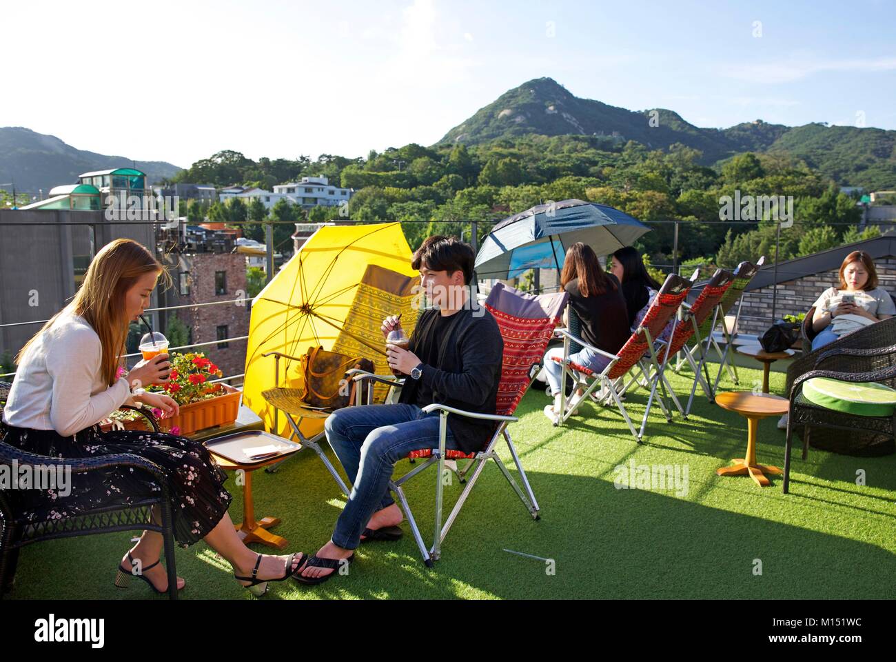 South Korea, Seoul, young people in the terrace of the coffe shop Alley forest in the district of Samcheong dong, in front of treed hills Stock Photo