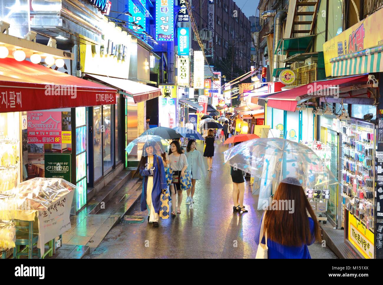 South Korea, Seoul, young people, umbrellas in hand, in the trendy district of Hongdae lit by neon Stock Photo