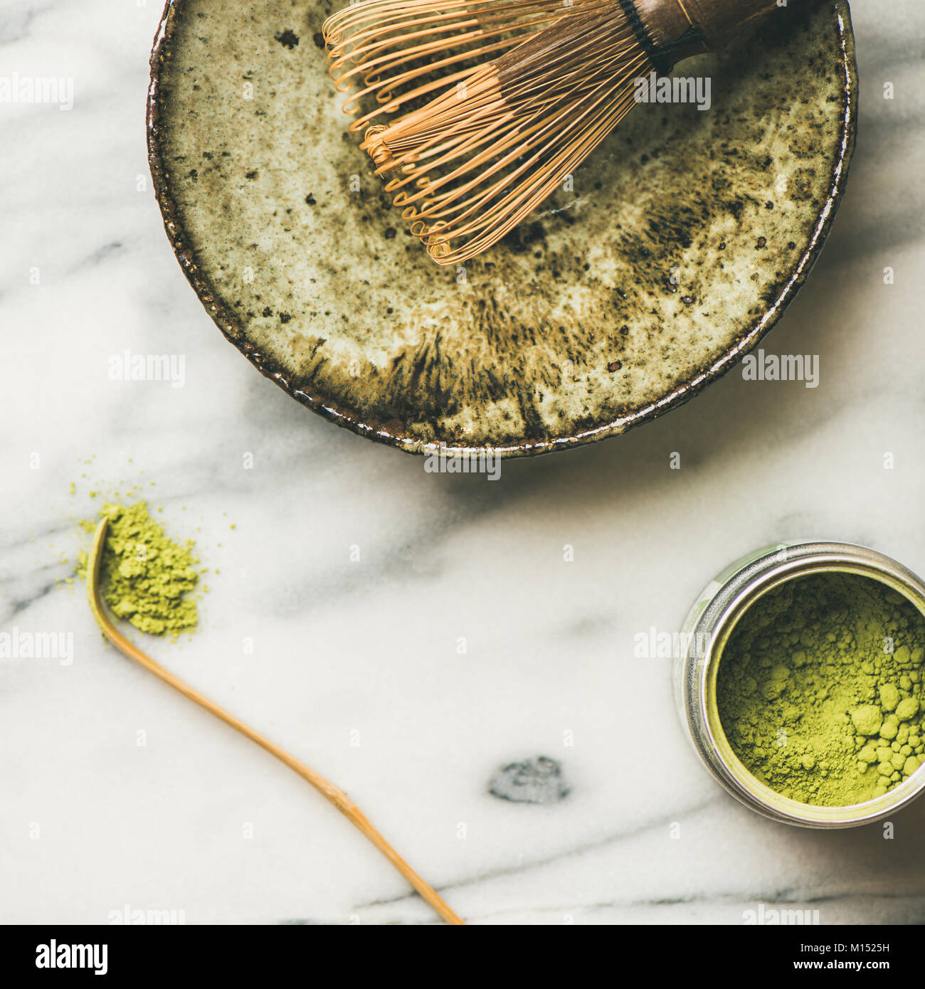 Flat-lay of Japanese tools for brewing matcha tea. Matcha powder in tin can, Chashaku spoon, Chasen bamboo whisk, Chawan bowl, cups for ceremony, grey Stock Photo