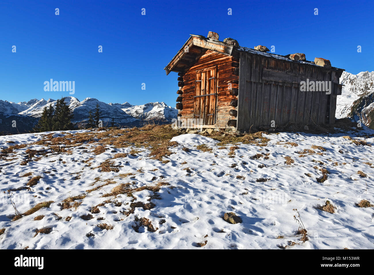 Wooden hut above the Lech valley at sunny winter day. View to the Lechtal Alps. Tirol, Austria Stock Photo