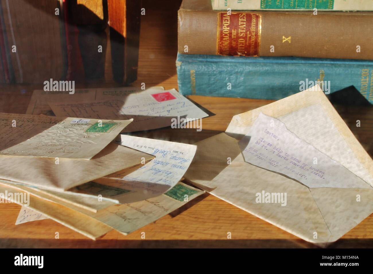 pile of old stamped letters and envelopes with antique books in background Stock Photo