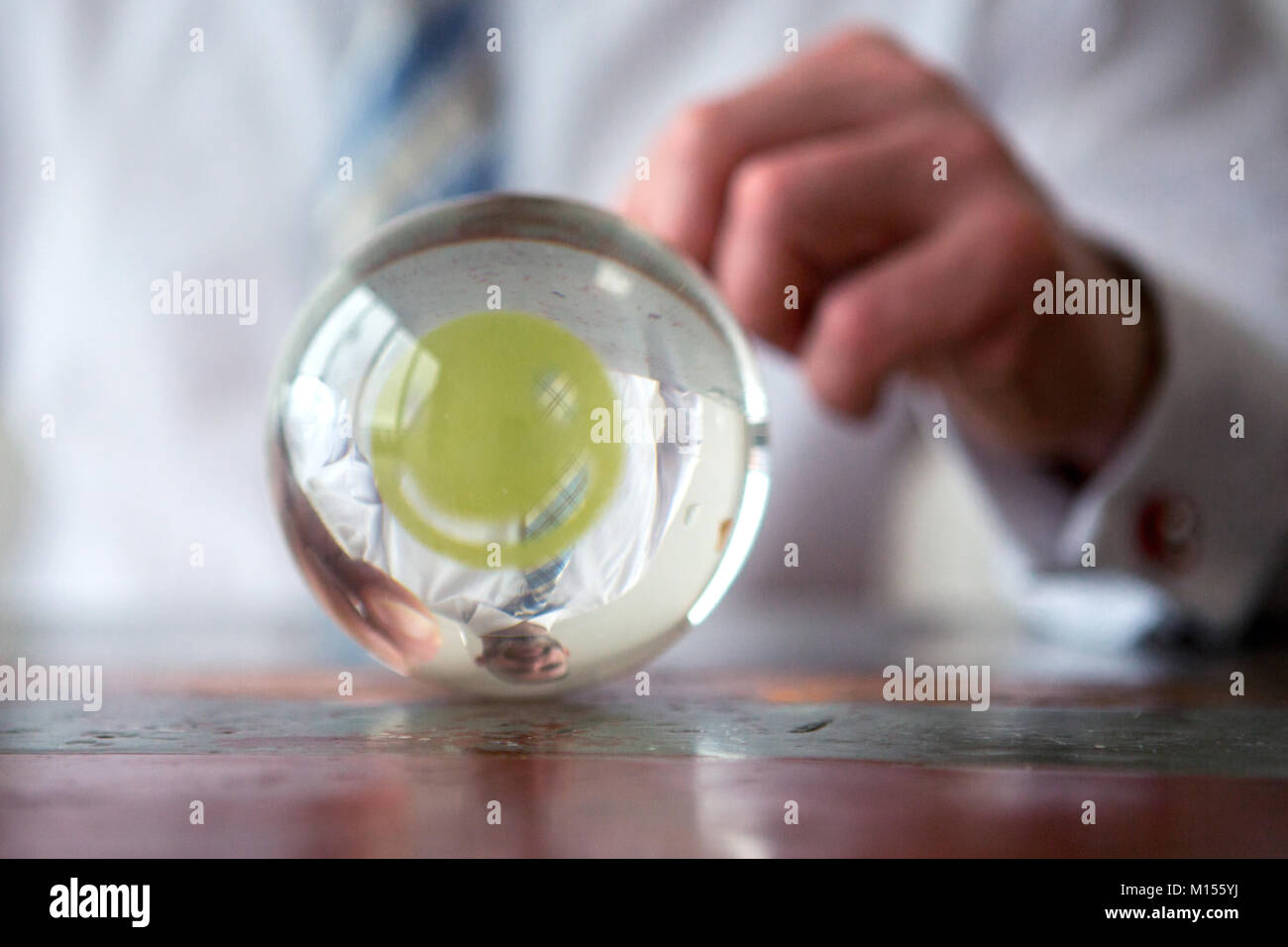 closeup of man holding paper with smiley face in front of glass ball Stock Photo