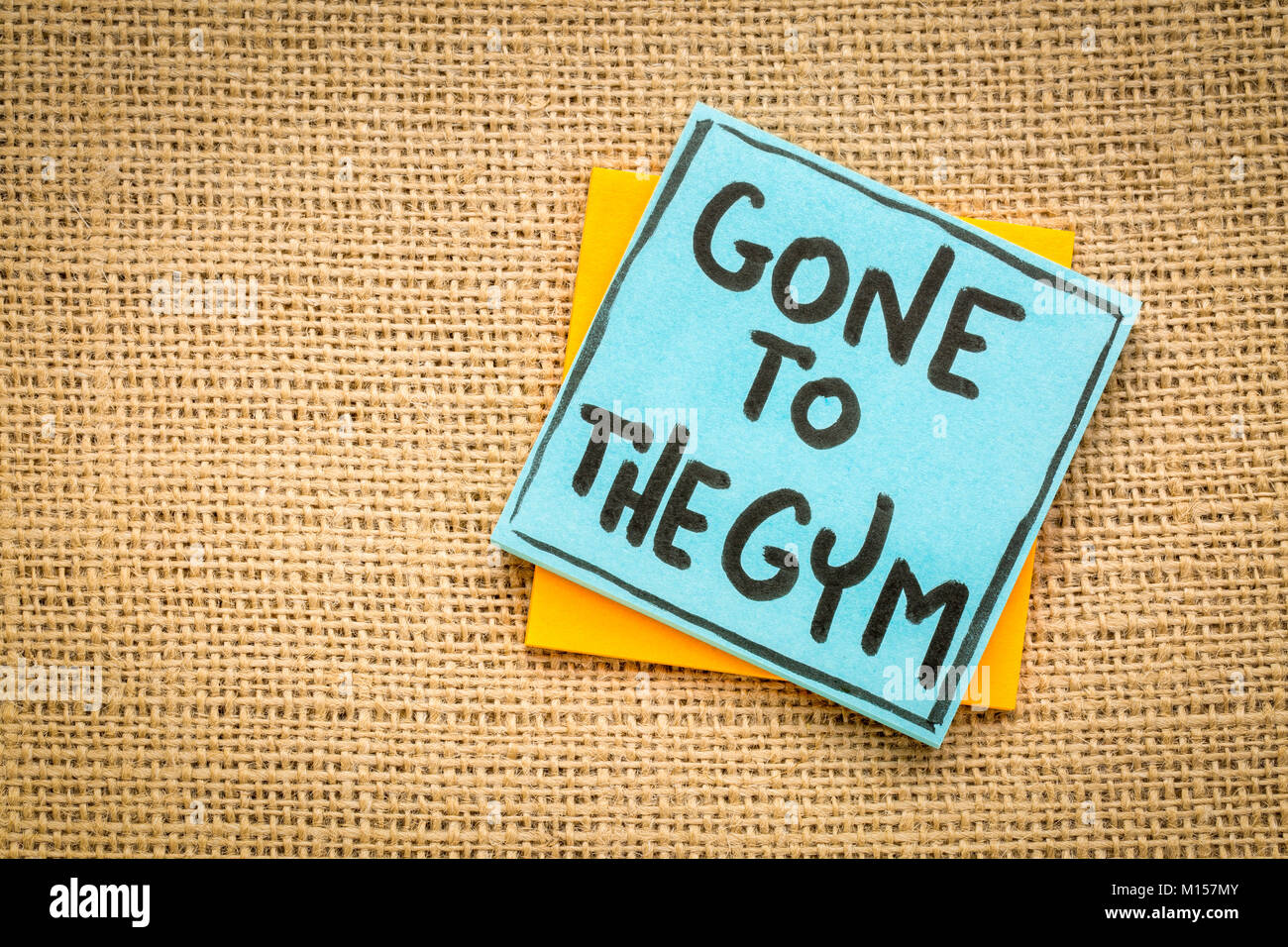 Gone to the gym handwriting on a sticky note against burlap canvas