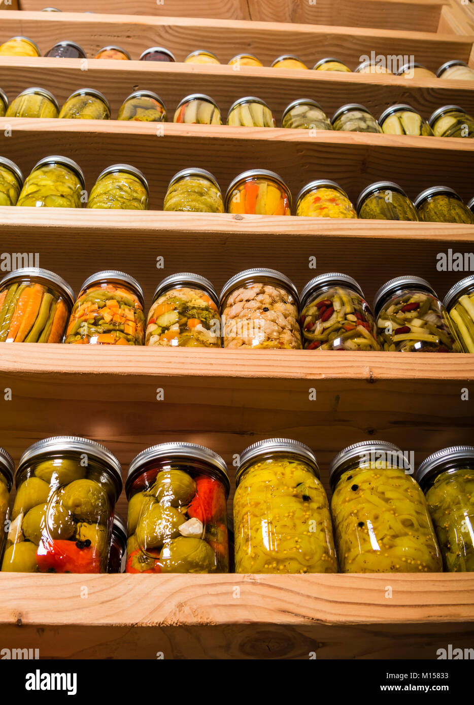 Jars of home canned fruits and vegetables on wooden shelves Stock Photo